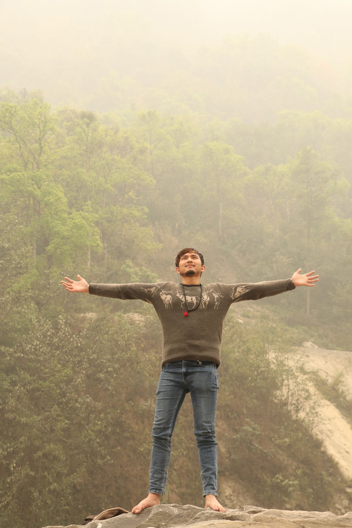 Nepali boy Wilson Shrestha on top of a big rock beside the Trisuli River